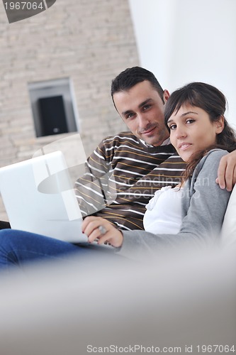 Image of joyful couple relax and work on laptop computer at modern home