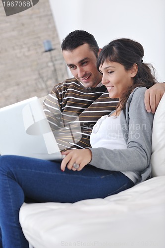 Image of joyful couple relax and work on laptop computer at modern home