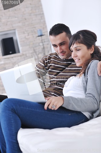 Image of joyful couple relax and work on laptop computer at modern home