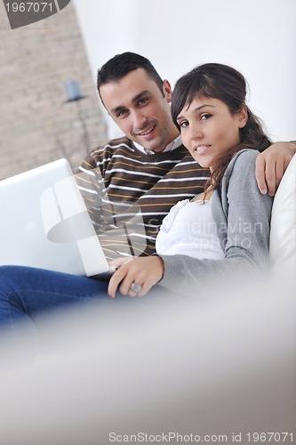 Image of joyful couple relax and work on laptop computer at modern home
