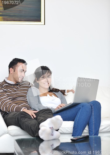 Image of joyful couple relax and work on laptop computer at modern home