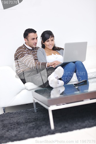 Image of joyful couple relax and work on laptop computer at modern home