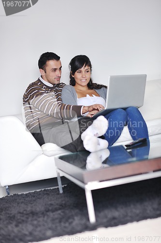 Image of joyful couple relax and work on laptop computer at modern home