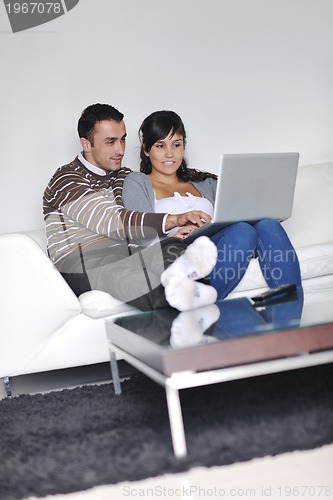 Image of joyful couple relax and work on laptop computer at modern home