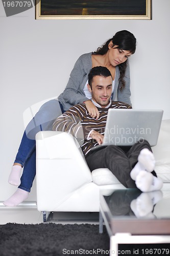 Image of joyful couple relax and work on laptop computer at modern home