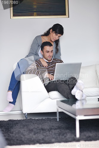 Image of joyful couple relax and work on laptop computer at modern home