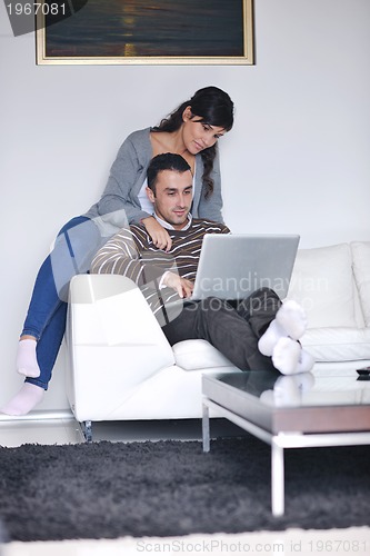 Image of joyful couple relax and work on laptop computer at modern home