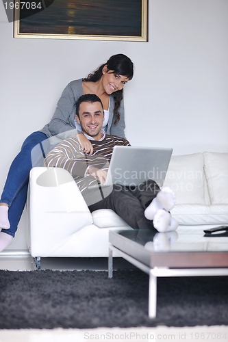 Image of joyful couple relax and work on laptop computer at modern home