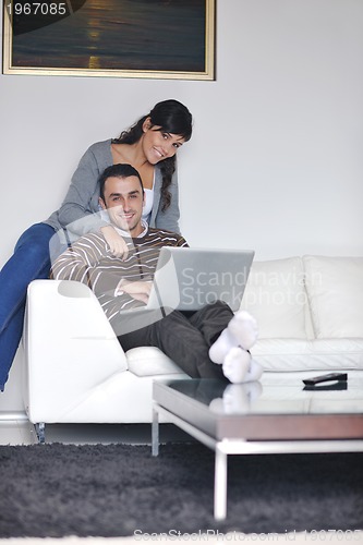 Image of joyful couple relax and work on laptop computer at modern home