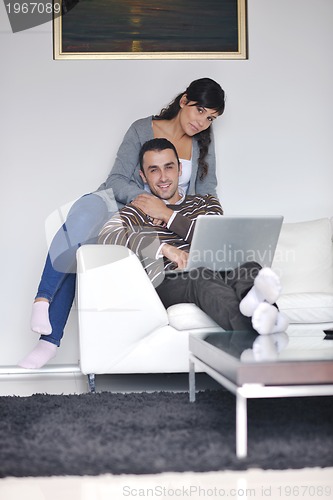 Image of joyful couple relax and work on laptop computer at modern home