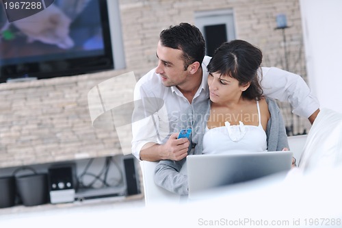Image of joyful couple relax and work on laptop computer at modern home