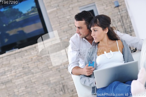 Image of joyful couple relax and work on laptop computer at modern home
