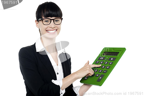 Image of Bespectacled woman using big green calculator