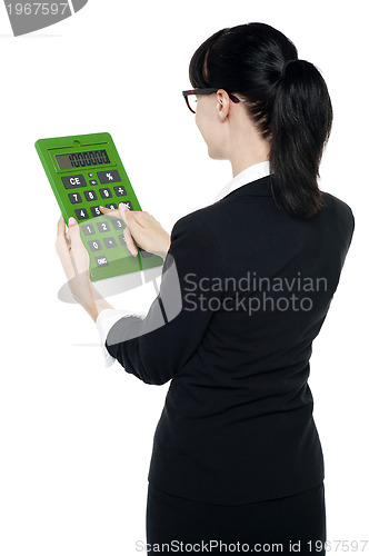 Image of Rear view of corporate woman using green calculator