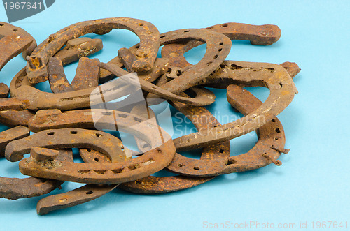 Image of stack of old retro horse shoes on blue 