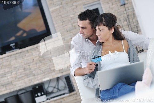 Image of joyful couple relax and work on laptop computer at modern home