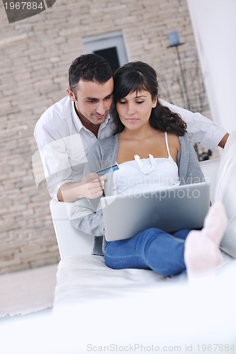 Image of joyful couple relax and work on laptop computer at modern home