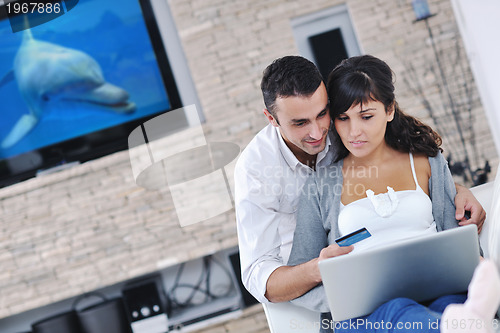 Image of joyful couple relax and work on laptop computer at modern home