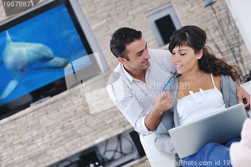 Image of joyful couple relax and work on laptop computer at modern home