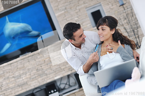 Image of joyful couple relax and work on laptop computer at modern home