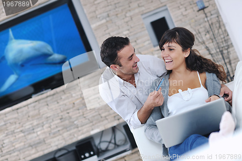 Image of joyful couple relax and work on laptop computer at modern home