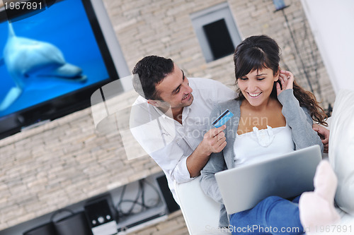 Image of joyful couple relax and work on laptop computer at modern home