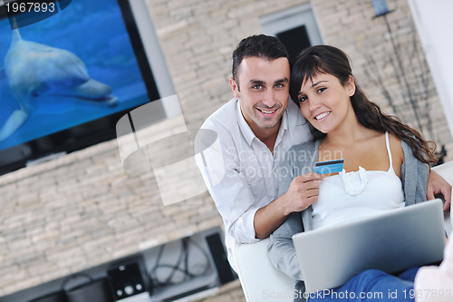 Image of joyful couple relax and work on laptop computer at modern home