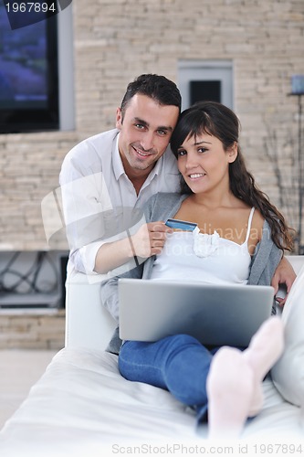 Image of joyful couple relax and work on laptop computer at modern home
