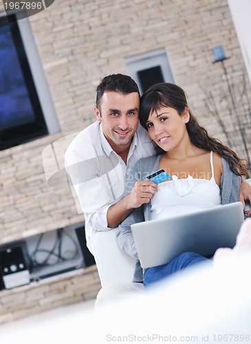 Image of joyful couple relax and work on laptop computer at modern home