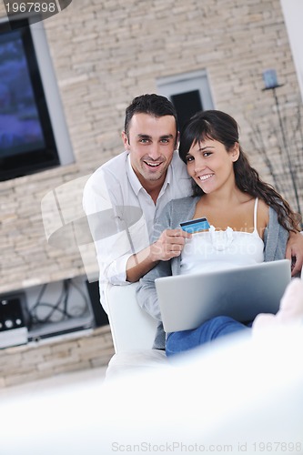 Image of joyful couple relax and work on laptop computer at modern home