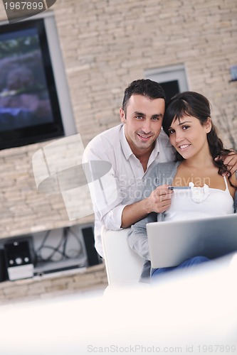 Image of joyful couple relax and work on laptop computer at modern home