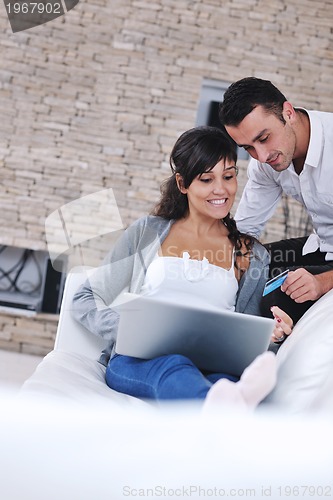 Image of joyful couple relax and work on laptop computer at modern home