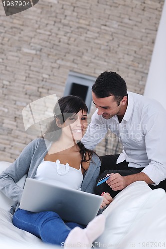 Image of joyful couple relax and work on laptop computer at modern home