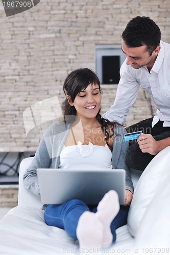 Image of joyful couple relax and work on laptop computer at modern home