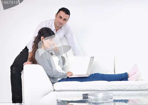 Image of joyful couple relax and work on laptop computer at modern home