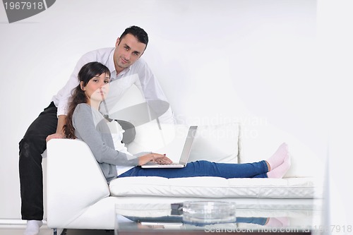 Image of joyful couple relax and work on laptop computer at modern home