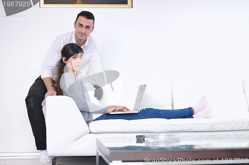 Image of joyful couple relax and work on laptop computer at modern home