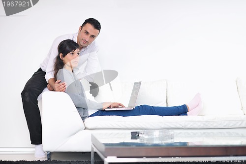 Image of joyful couple relax and work on laptop computer at modern home