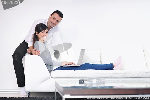 Image of joyful couple relax and work on laptop computer at modern home