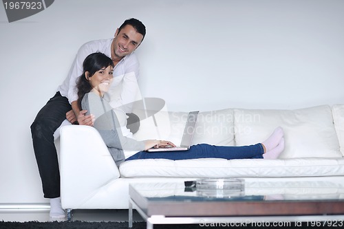 Image of joyful couple relax and work on laptop computer at modern home