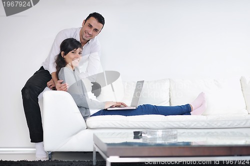 Image of joyful couple relax and work on laptop computer at modern home