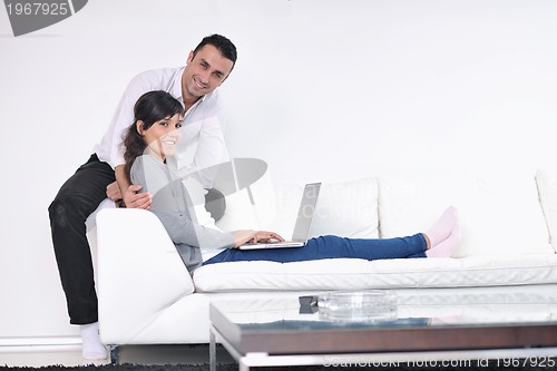 Image of joyful couple relax and work on laptop computer at modern home