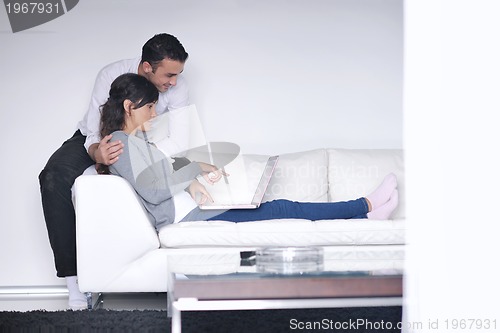Image of joyful couple relax and work on laptop computer at modern home