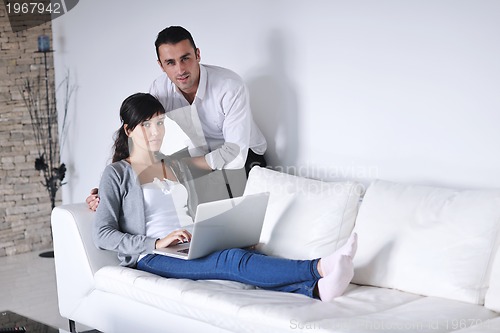 Image of joyful couple relax and work on laptop computer at modern home