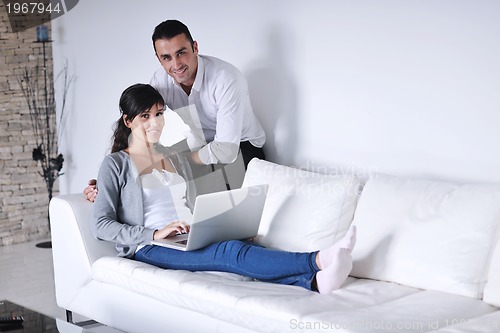 Image of joyful couple relax and work on laptop computer at modern home
