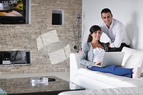 Image of joyful couple relax and work on laptop computer at modern home