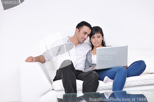 Image of joyful couple relax and work on laptop computer at modern home