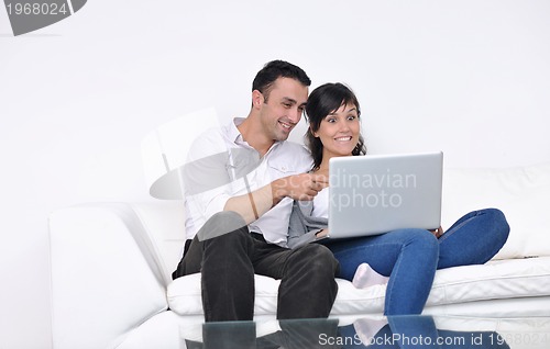 Image of joyful couple relax and work on laptop computer at modern home
