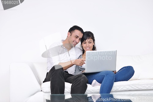 Image of joyful couple relax and work on laptop computer at modern home