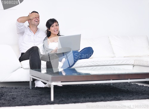 Image of joyful couple relax and work on laptop computer at modern home